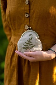 a woman in a brown dress is holding a small bag with a plant on it