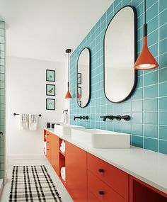 a bathroom with blue and orange tiles on the walls, two mirrors above the sinks