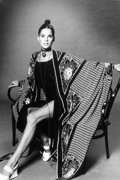 a woman sitting on top of a chair next to a blanket