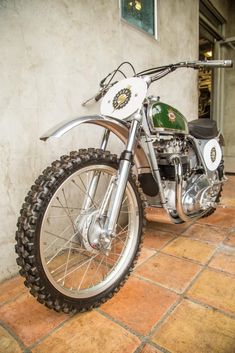 a dirt bike parked on top of a tiled floor next to a white brick wall