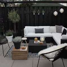 an outdoor living area with black and white furniture, potted plants and other decorations