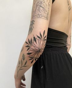 a woman's arm with tattoos on it and flowers in the middle of her arm