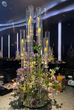 a vase filled with candles and flowers on top of a table next to other tables