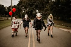 three women in costumes are walking down the street with clowns on their heads and legs