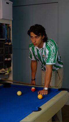 a man is leaning over to pick up balls on a pool table in an office