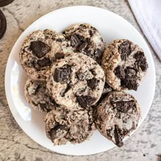 chocolate chip cookies on a white plate next to an oreo cookie and a glass of milk