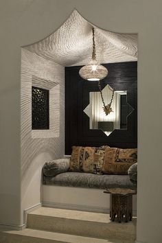 a black and white photo of a living room with a couch in the corner, mirror on the wall