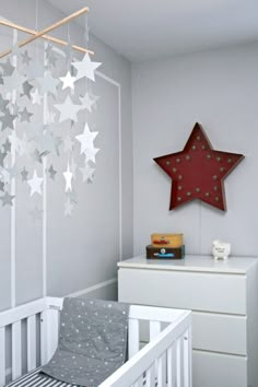 a baby's room with a white crib and stars hanging from the ceiling