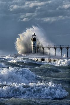 a lighthouse in the ocean with waves crashing over it