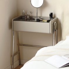 there is a small vanity with a mirror on it in the corner next to a bed