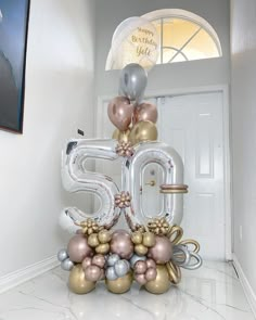 the balloon number 50 is decorated with gold, silver and pink balloons