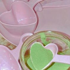 two heart shaped sugar spoons sitting in a jar next to other pink and white dishes