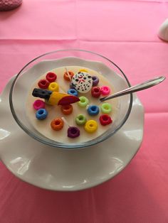 a white plate topped with a bowl filled with cereal covered in colorful candies and sprinkles