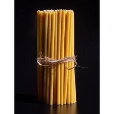 several yellow candles tied with twine on black background