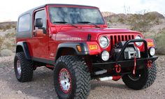 a red jeep is parked in the desert