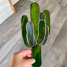 a person holding up a green glass cactus