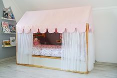 a child's bedroom with a pink canopy bed and white curtains on the walls