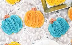 decorated cookies with blue, yellow and orange frosting on a doily tablecloth