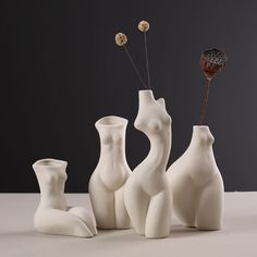 three white vases with flowers in them sitting on a table next to each other