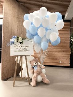 a teddy bear sitting next to a bunch of balloons