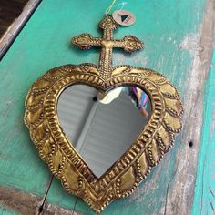 a heart shaped mirror hanging on the side of a wooden table with a cross in it