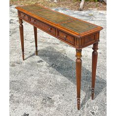 an old wooden table with two drawers on one side and a leather top on the other