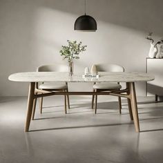 a dining table with chairs and a vase on it in a room that has white walls