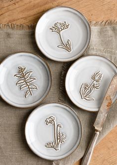 four plates with flowers on them are sitting on a table next to a knife and fork