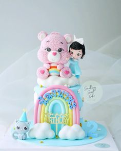 there is a birthday cake with a teddy bear on top and a rainbow in the middle