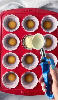 someone using a plastic spoon to mix batter into cupcakes in a muffin tin