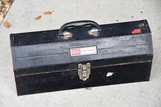 an old black suitcase is sitting on the cement outside with its lid open and handle missing