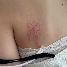 a woman's breast with a red bow tattoo on it