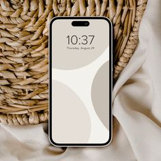 an iphone sitting on top of a wicker basket next to a white cloth covered table