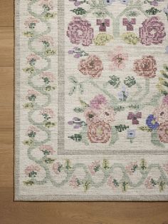 a white rug with flowers and vines on the bottom is laying on a wooden floor