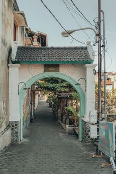 an archway leading to a building with plants growing on it