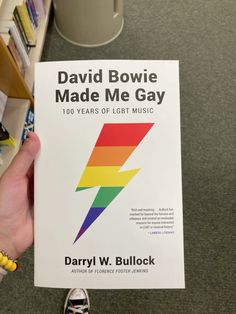 a person holding up a book about david bowie made me gay