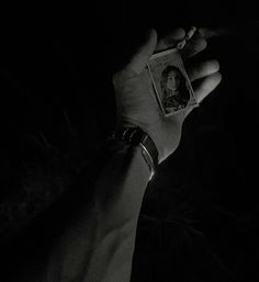 a hand holding an old photo in the dark