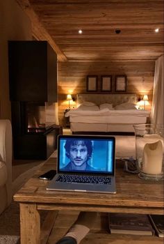 a laptop computer sitting on top of a wooden table in front of a bedroom with a bed