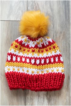 a red and white knitted hat with a yellow pom - pom on top