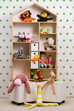 there are many stuffed animals on the shelves in this playroom with polka dot wallpaper