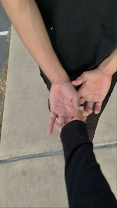 two people holding hands on the sidewalk with one pointing at the other's hand