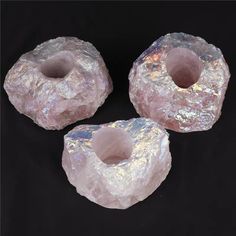 three pieces of pink rock sitting on top of a black surface