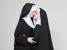 two women dressed in nun costumes kissing each other