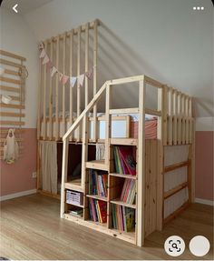 a loft bed with bookshelves and shelves in the middle, on top of a wooden floor