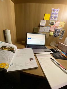 an open book sitting on top of a desk next to a laptop computer and other items