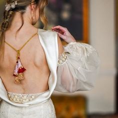 the back of a woman's wedding dress with an elaborate necklace on her neck