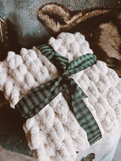 two white knitted sweaters wrapped in green and white checkered ribbon with a bow