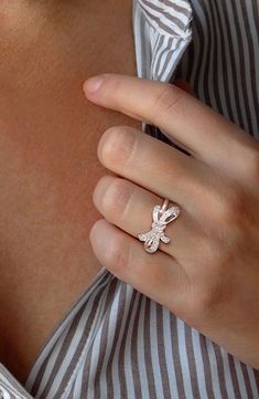 a woman's hand with a ring on her left side, wearing a striped shirt