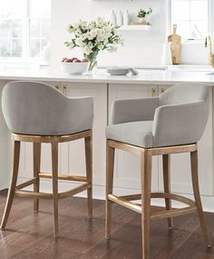 two gray chairs sitting on top of a wooden floor in front of a white counter