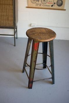 a wooden stool sitting in front of a painting on the wall next to a bar stool